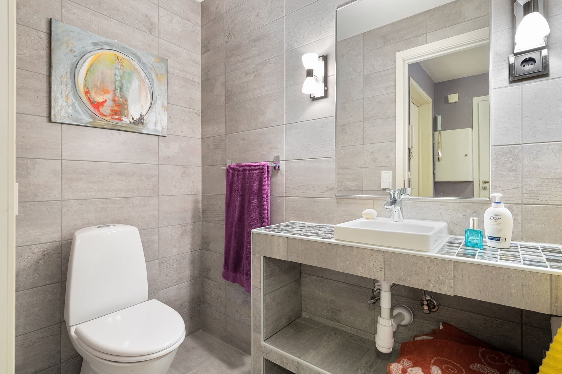 The replacement primary bath, tiled wall to wall with the vanity set on an open stone base.