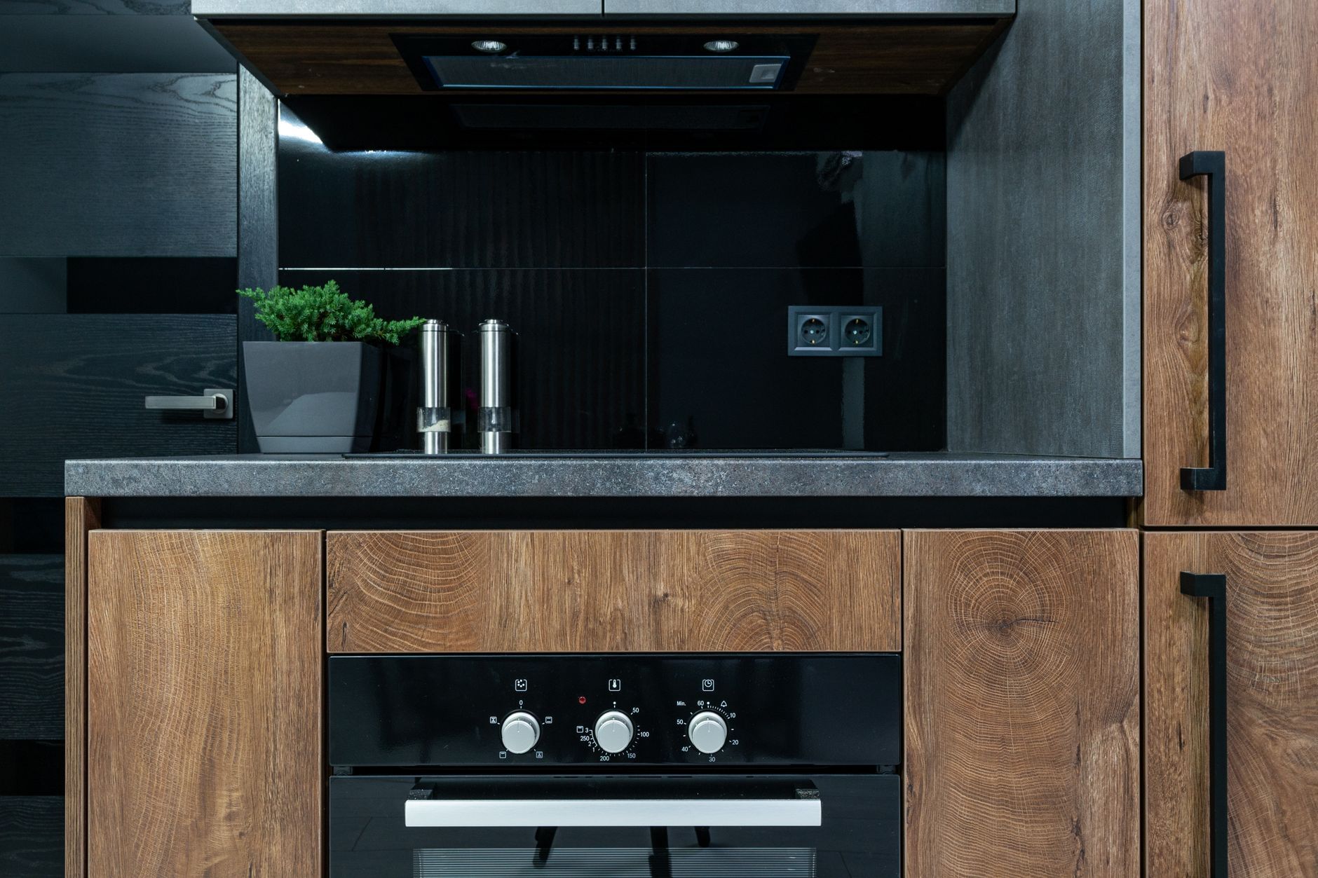 The finished kitchen: oak fronts, a stone counter and the new range wall standing where the partition to the dining room used to be.