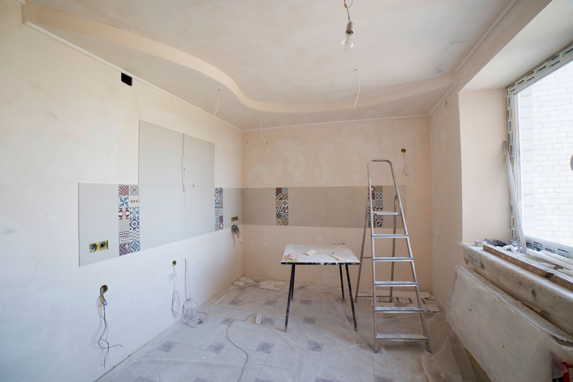 The garage mid-conversion: walls floated, the new window opening framed and the ceiling ready for finish.